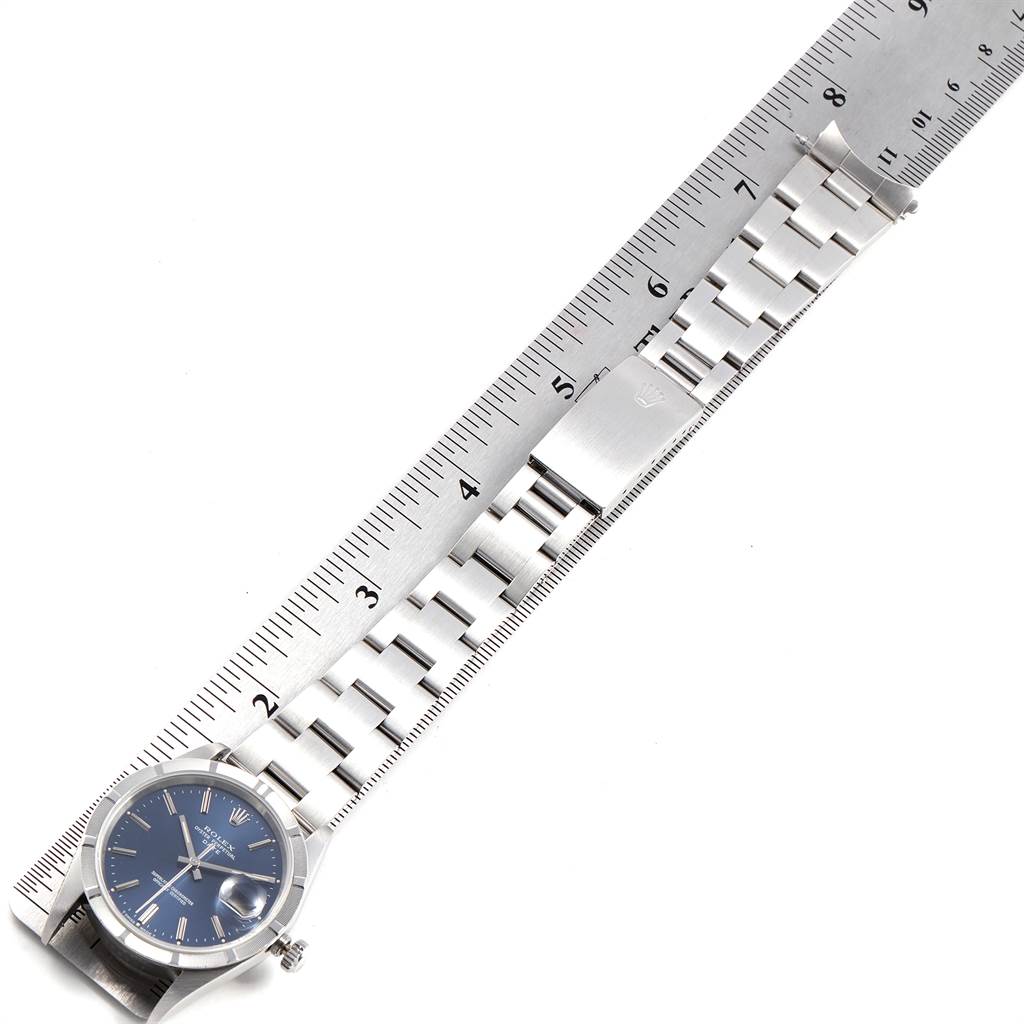 The Rolex Date 15210 Men's Stainless Steel Blue Dial 15210 Men's Stainless Steel Blue Dial model watch is shown from a top-down angle, displaying the face, bracelet, and clasp aligned with a ruler.