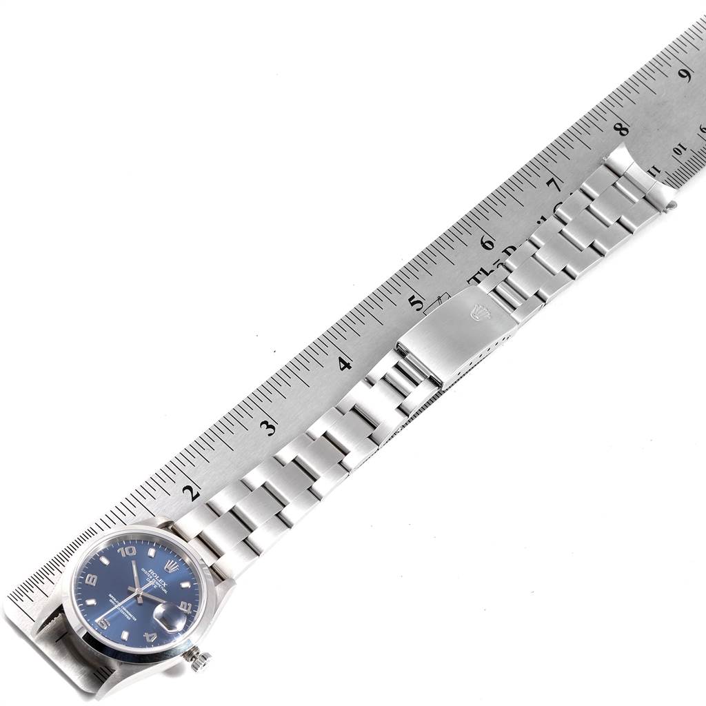 The Rolex Date 15200 Men's Stainless Steel Blue Dial 15200 Men's Stainless Steel Blue Dial model watch is shown from a top-down angle, highlighting the face, metal band, and clasp beside a ruler for size reference.