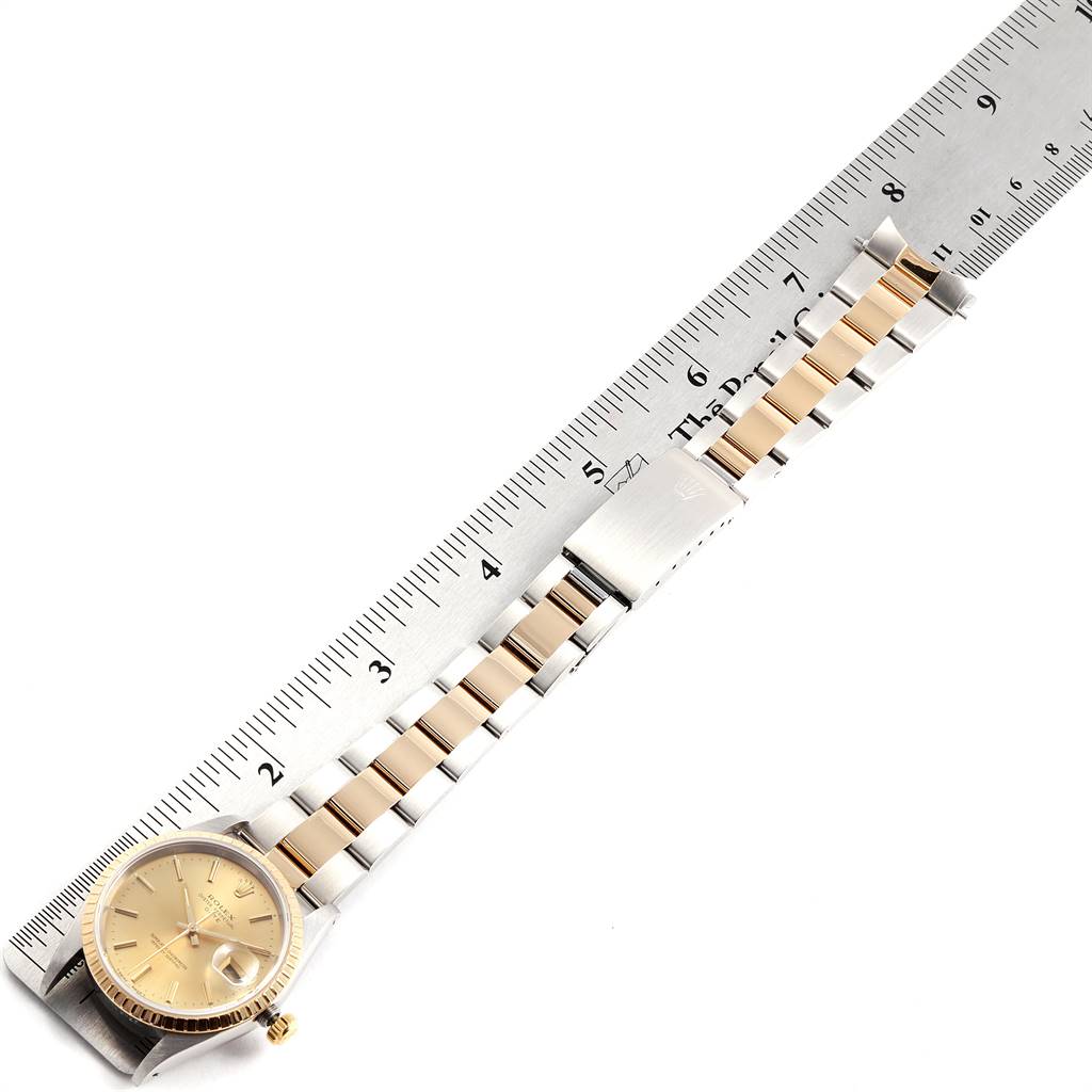 The Rolex Date 15223 Men's Steel and Gold (two tone) Champagne Dial 15223 Men's Steel and Gold (two tone) Champagne Dial model watch is shown from a top view, including the dial, bracelet, and clasp, with a ruler for scale.
