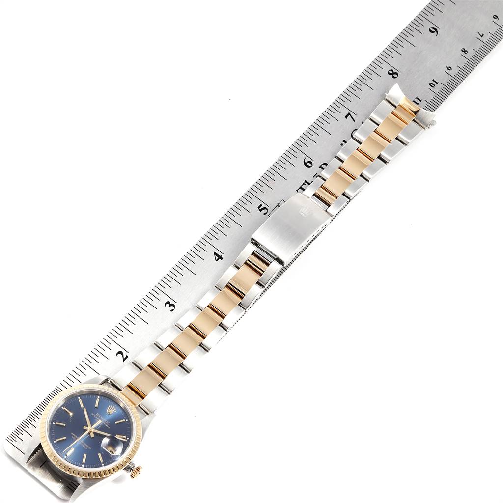 The image shows a Rolex Date 15223 Men's Steel and Gold (two tone) Blue Dial 15223 Men's Steel and Gold (two tone) Blue Dial model watch laid flat alongside a ruler, displaying the entire watch and bracelet.