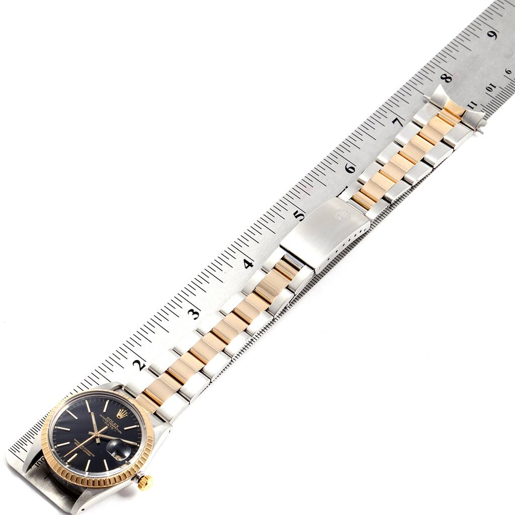 This image shows the Rolex Date 15053 Men's Steel and Gold (two tone) Black Dial 15053 Men's Steel and Gold (two tone) Black Dial model watch laid flat with a ruler, displaying the full bracelet and face.