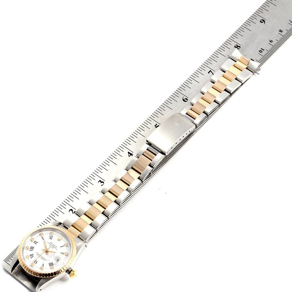 The image shows a Rolex Date 15223 Men's Steel and Gold (two tone) White Dial 15223 Men's Steel and Gold (two tone) White Dial model watch with a silver and gold bracelet laid out alongside a ruler, showcasing its length.