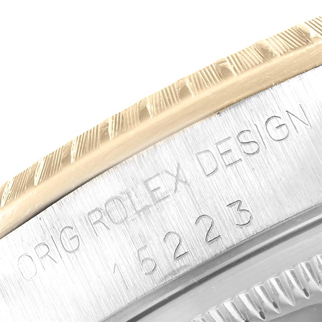 The image shows a close-up of the bezel and engraved case side of a Rolex Date 15223 Men's Steel and Gold (two tone) Silver Dial 15223 Men's Steel and Gold (two tone) Silver Dial model watch.