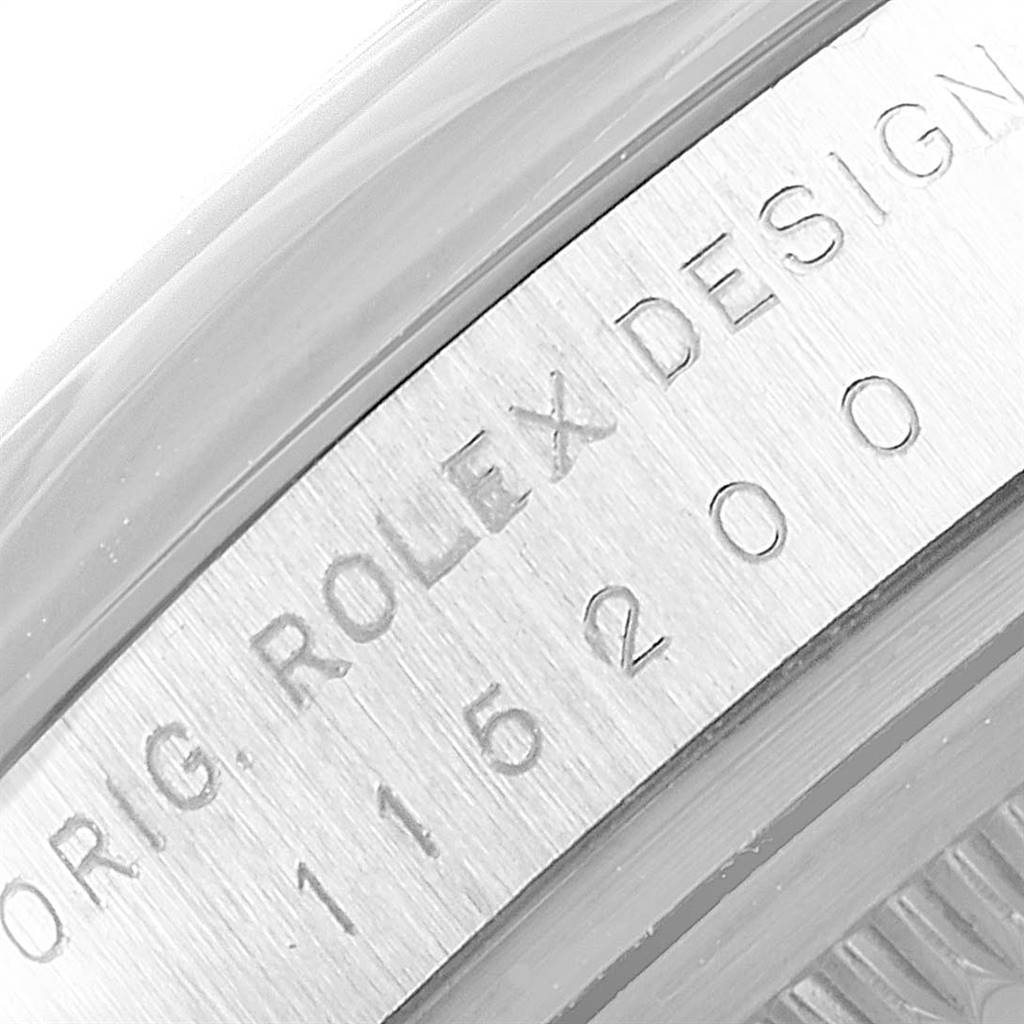 This close-up image of the Rolex Date 115200 Men's Stainless Steel Black Dial 115200 Men's Stainless Steel Black Dial model watch showcases the engraved "ROLEX DESIGN" and model number on the case.