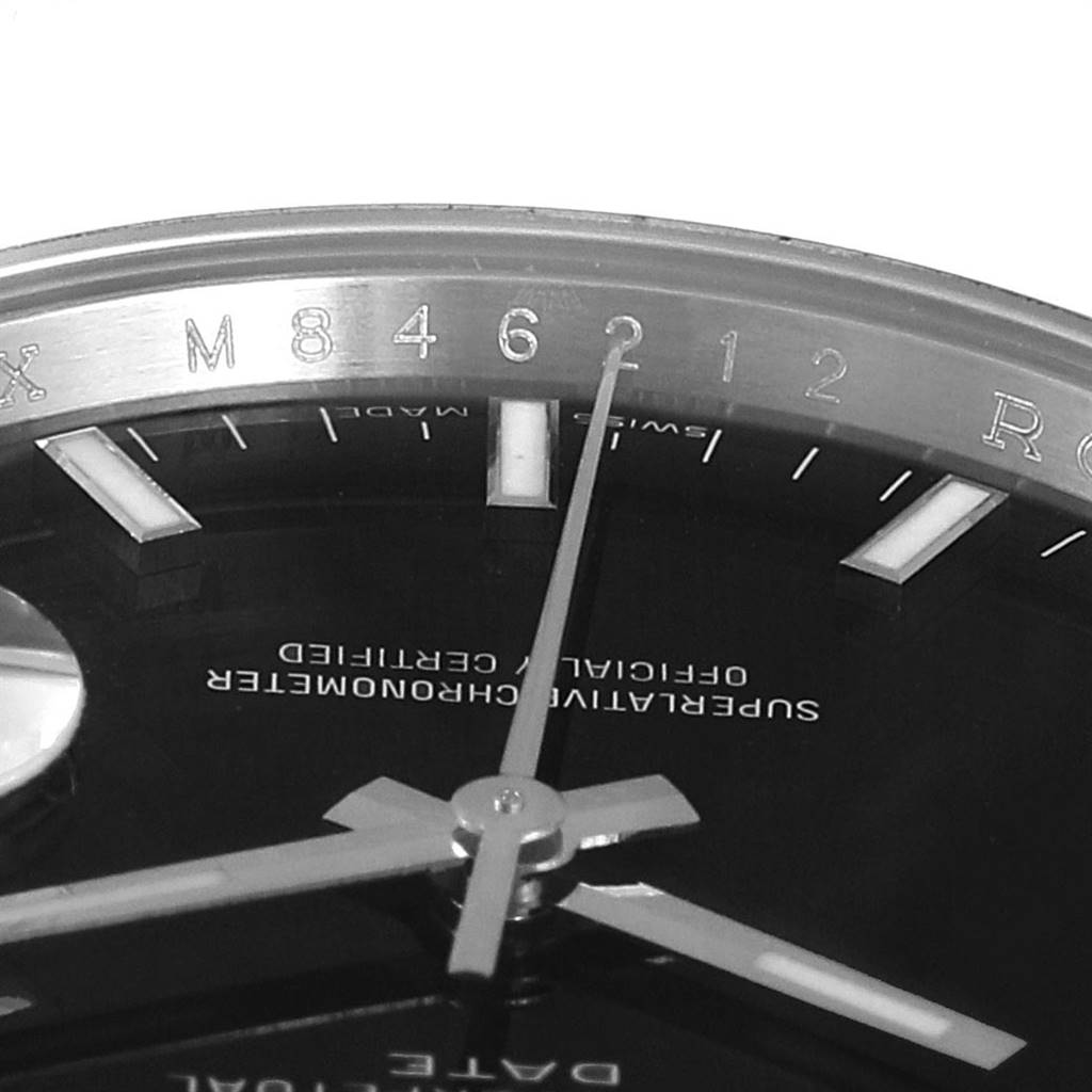 The image shows a close-up of the dial and hands of a Rolex Date 115200 Men's Stainless Steel Black Dial 115200 Men's Stainless Steel Black Dial model watch, focusing on the hour markers and text on the dial.