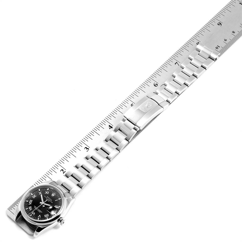The image shows a Rolex Date 115200 Men's Stainless Steel Black Dial 115200 Men's Stainless Steel Black Dial watch with a metal bracelet at an angle, measured against a ruler.