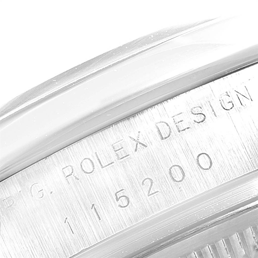 The image shows an angled close-up of the casing with the engraved serial number of the Rolex Date 115200 Men's Stainless Steel Black Dial 115200 Men's Stainless Steel Black Dial model watch.