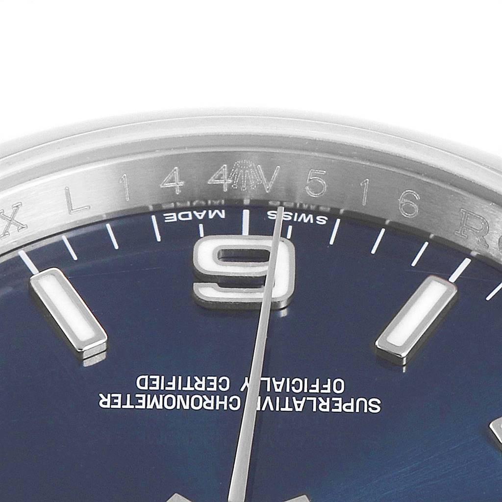 This close-up image of the Rolex Date 116000 Men's Stainless Steel Blue Dial 116000 Men's Stainless Steel Blue Dial model shows part of the dial with indices and numbers, plus the Rolex logo and text.