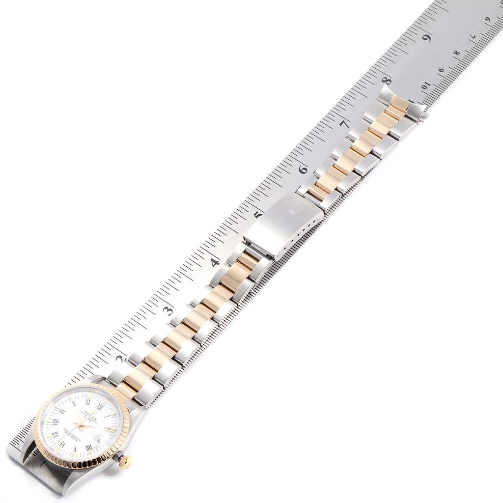 The image shows a Rolex Date 15223 Men's Steel and Gold (two tone) White Dial 15223 Men's Steel and Gold (two tone) White Dial model watch placed diagonally on a ruler, highlighting the band and part of the dial.