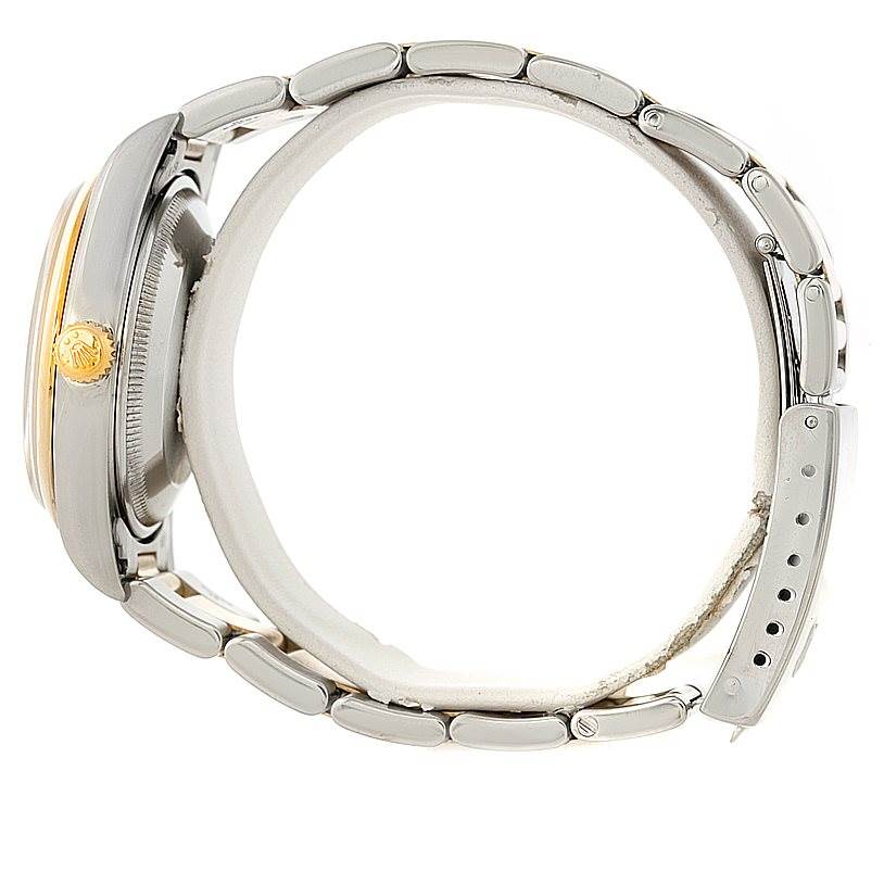 This side view showcases the Rolex Date 15203 Men's Steel and Gold (two tone) Grey Dial 15203 Men's Steel and Gold (two tone) Grey Dial model's case, crown, and partial bracelet.