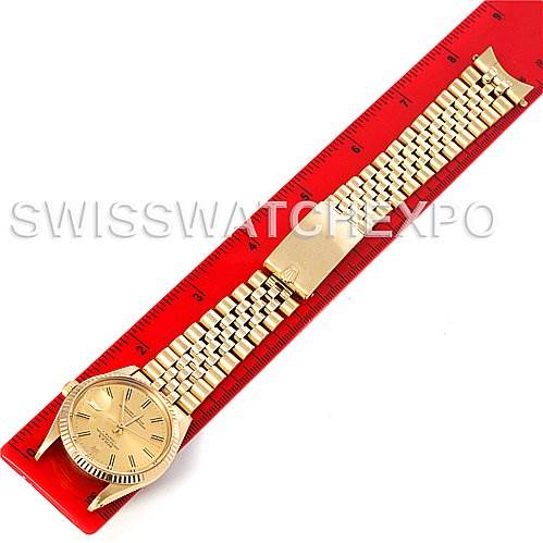 The image shows a Rolex Date 15037 Men's Yellow Gold Champagne Dial 15037 Men's Yellow Gold Champagne Dial model watch laid flat on a red ruler, highlighting the dial, bezel, and bracelet.