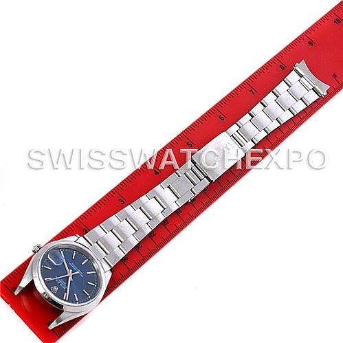 This image shows a Rolex Date 15200 Men's Stainless Steel Blue Dial 15200 Men's Stainless Steel Blue Dial model watch laid flat against a red ruler, displaying its bracelet and blue dial from an aerial view.