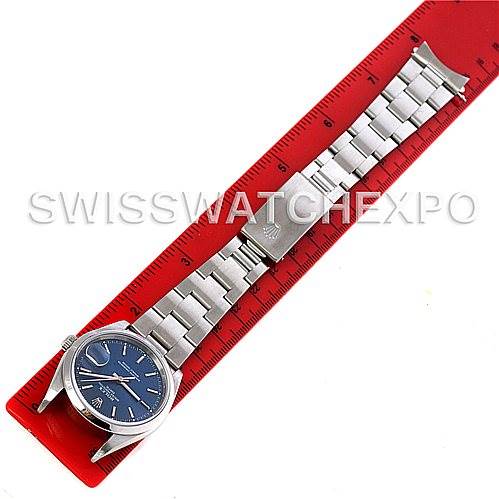 The Rolex Date 15200 Men's Stainless Steel Blue Dial 15200 Men's Stainless Steel Blue Dial watch is shown flat with its bracelet fully extended on a red ruler.