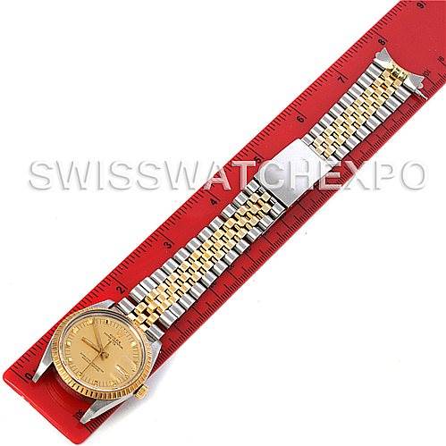 The Rolex Date 15053 Men's Stainless Steel Champagne Dial 15053 Men's Stainless Steel Champagne Dial model watch is shown from a top-down angle, displaying the face, bezel, and bracelet on a ruler.