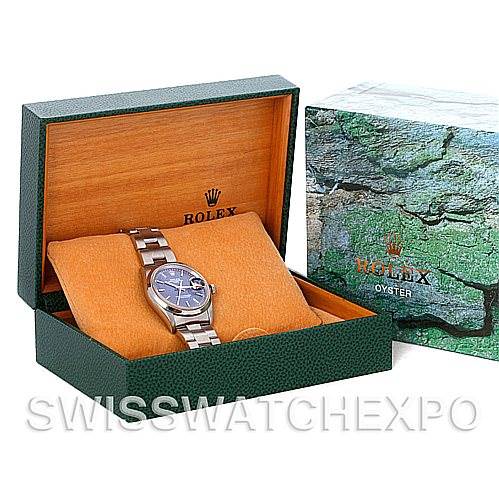 The image shows a Rolex Date 15200 Men's Stainless Steel Blue Dial 15200 Men's Stainless Steel Blue Dial watch in a green and wooden box with the exterior packaging next to it.