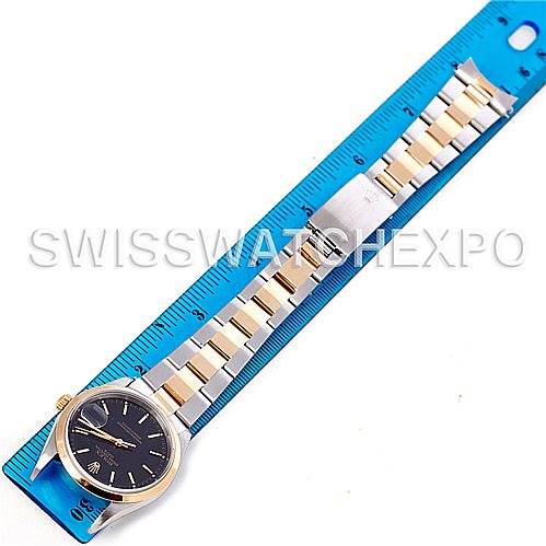 This image shows a Rolex Date 15203 Men's Steel and Gold (two tone) Black Dial 15203 Men's Steel and Gold (two tone) Black Dial model watch with a two-tone bracelet laid next to a blue ruler, displaying the entire watch and strap.