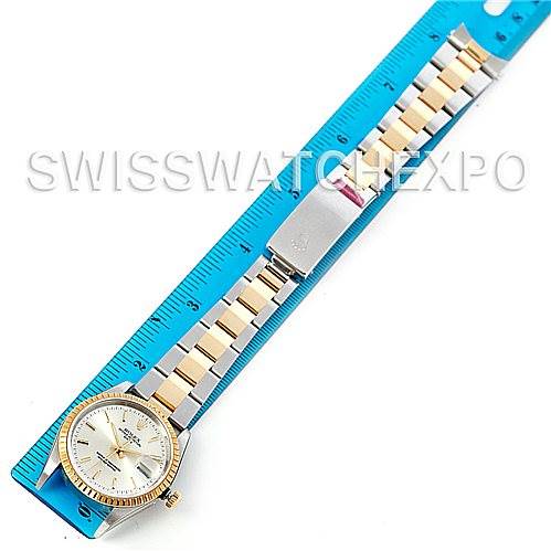 The image shows a Rolex Date 15223 Men's Steel and Gold (two tone) Silver Dial 15223 Men's Steel and Gold (two tone) Silver Dial model watch placed alongside a blue ruler, displaying the watch face and bracelet.