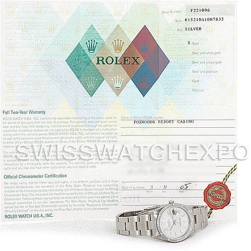 The image shows a Rolex Date 15210 Men's Stainless Steel Silver Dial 15210 Men's Stainless Steel Silver Dial model watch positioned at an angle with its face, bracelet, and warranty card visible.