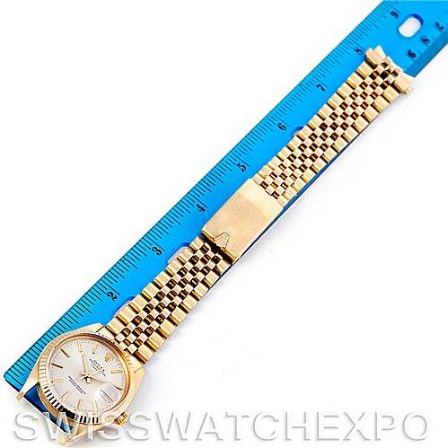 The Rolex Date 15037 Men's Yellow Gold Silver Dial 15037 Men's Yellow Gold Silver Dial model watch is shown fully extended next to a blue ruler, capturing the face, bracelet, and clasp.