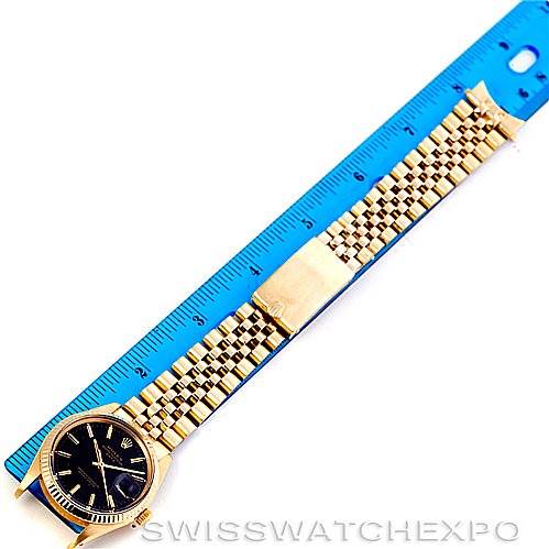 The image shows a top-down view of a Rolex Date 15037 Men's Yellow Gold Black Dial 15037 Men's Yellow Gold Black Dial watch with a gold bracelet placed next to a blue ruler.