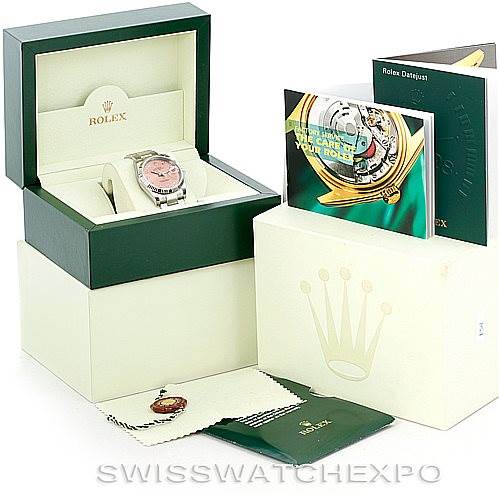 The image shows a Rolex Date 115234 Men's Stainless Steel Pink Dial 115234 Men's Stainless Steel Pink Dial model watch with its box, documents, and accessories from a slightly elevated angle.