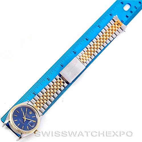 The image shows a top-down view of a Rolex Date 15223 Men's Steel and Gold (two tone) Blue Dial 15223 Men's Steel and Gold (two tone) Blue Dial model watch laid flat next to a blue ruler.