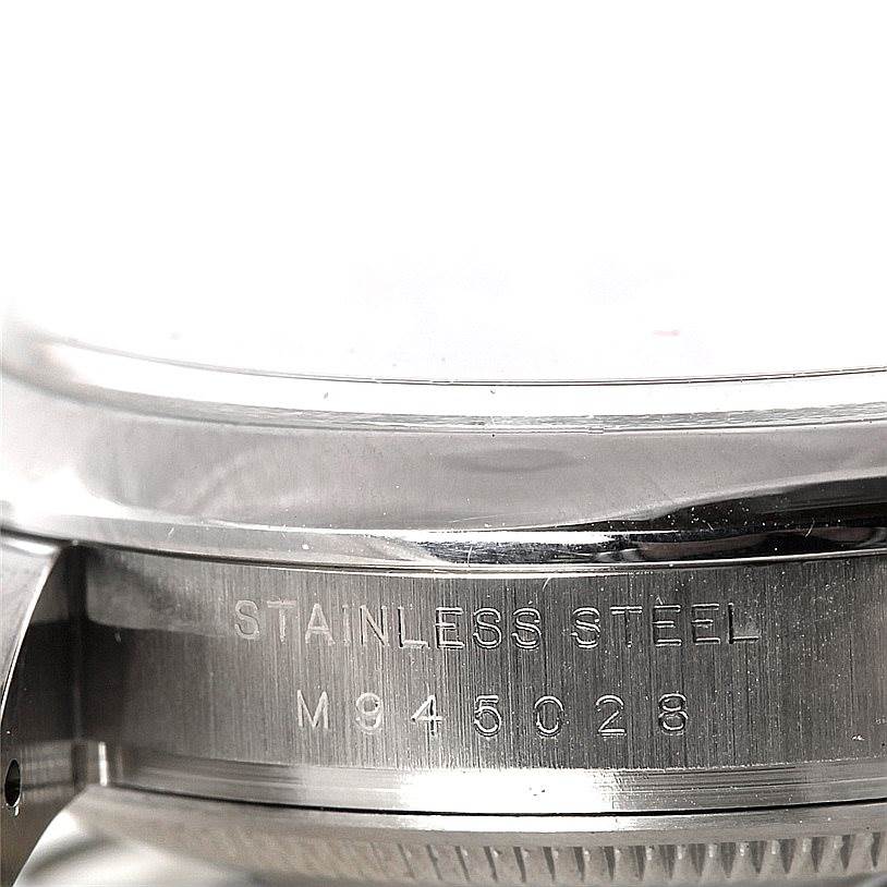 This close-up image shows the stainless steel casing and part of the side of a Rolex Date 115200 Men's Stainless Steel Blue Dial 115200 Men's Stainless Steel Blue Dial model, along with its inscription.