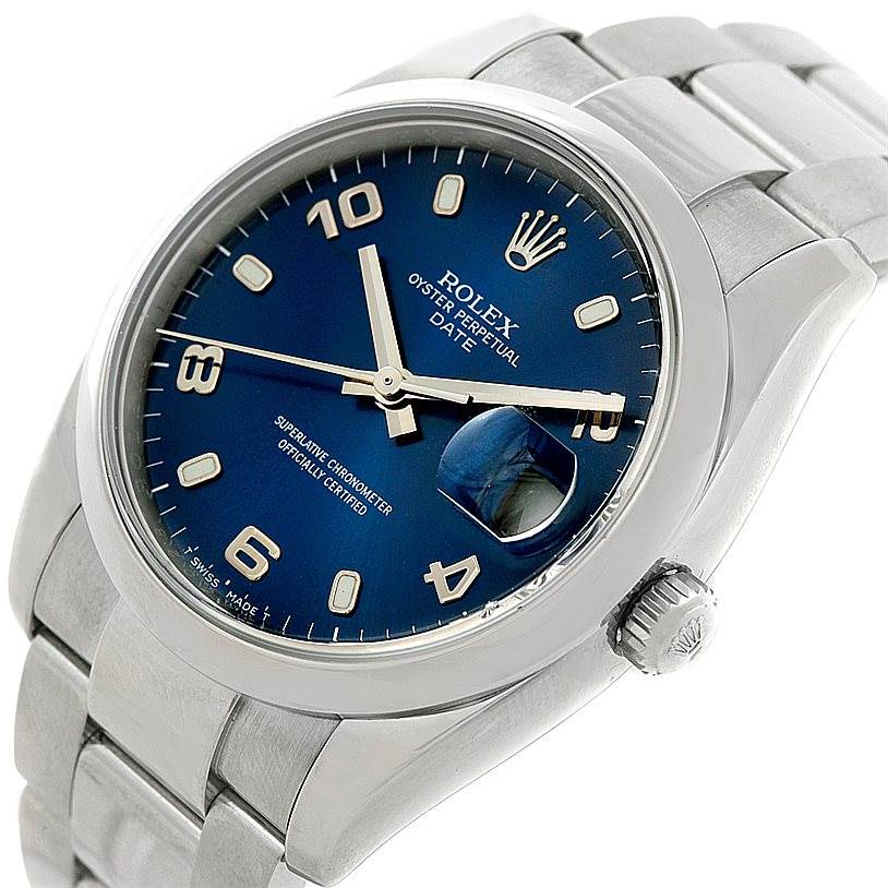 This image shows a Rolex Date 115200 Men's Stainless Steel Blue Dial 115200 Men's Stainless Steel Blue Dial model watch from a slightly tilted angle highlighting the face, bezel, crown, and bracelet.
