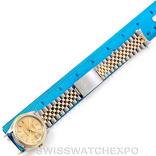 The Rolex Date 15223 Men's Steel and Gold (two tone) Champagne Dial 15223 Men's Steel and Gold (two tone) Champagne Dial watch is shown from an overhead angle, featuring a gold dial, jubilee bracelet, and a ruler for scale.