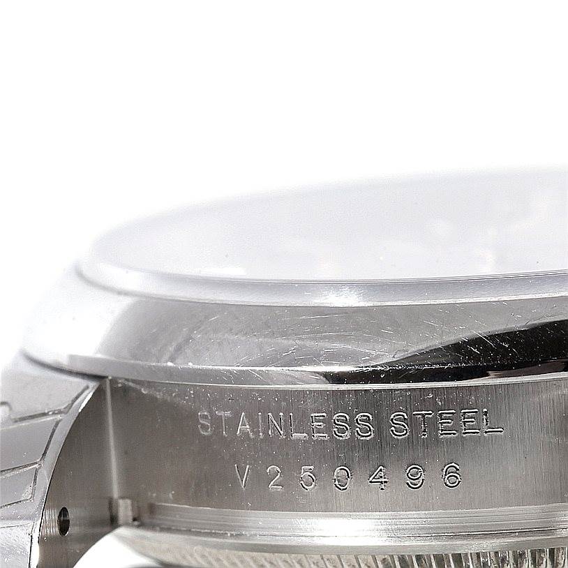 This image shows a close-up side angle of a Rolex Date 115200 Men's Stainless Steel Silver Dial 115200 Men's Stainless Steel Silver Dial model watch, highlighting the stainless steel case with its serial number.