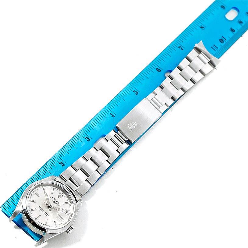 The image shows a Rolex Date 15200 Men's Stainless Steel Silver Dial 15200 Men's Stainless Steel Silver Dial model watch laid flat next to a measuring ruler, highlighting the watch's face, bracelet, and clasp.