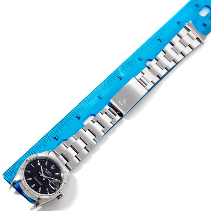 The image shows a Rolex Date 15210 Men's Stainless Steel Black Dial 15210 Men's Stainless Steel Black Dial model watch laid flat next to a ruler, displaying the face, bracelet, and clasp.