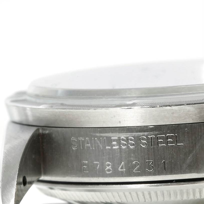 This close-up image of a Rolex Date 15210 Men's Stainless Steel Black Dial 15210 Men's Stainless Steel Black Dial model watch shows the side, including the bezel, case, and part of the lug, with the serial number engraved.