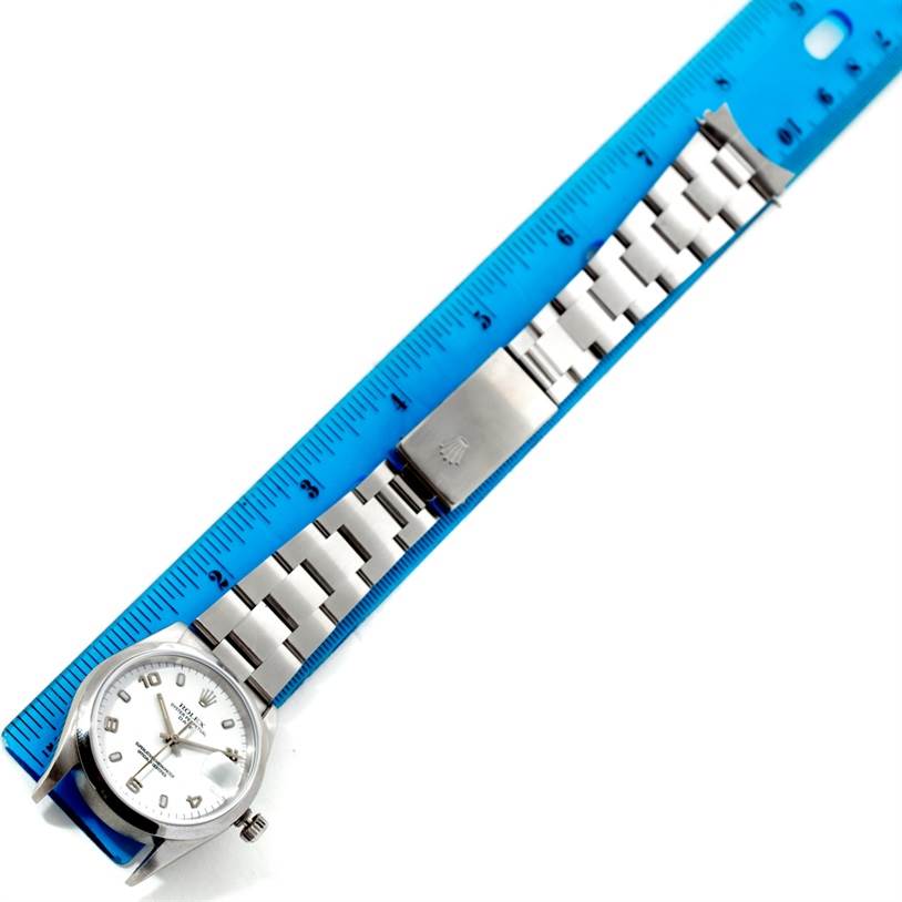 The image shows a top view of a Rolex Date 15200 Men's Stainless Steel White Dial 15200 Men's Stainless Steel White Dial watch laid next to a blue ruler, displaying the watch face and metal bracelet.