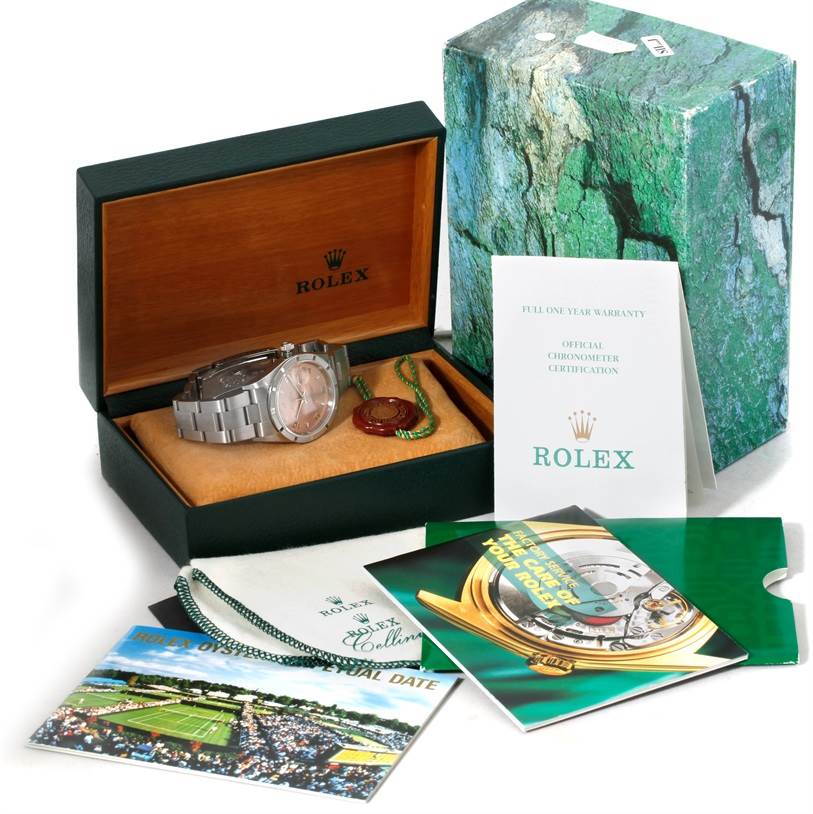 The Rolex Date 15210 Men's Stainless Steel Pink Dial 15210 Men's Stainless Steel Pink Dial model watch is displayed in an open box along with warranty cards, booklets, and a green outer box.