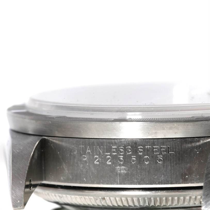 The image shows a close-up side view of the case of a Rolex Date 15210 Men's Stainless Steel Pink Dial 15210 Men's Stainless Steel Pink Dial model watch with the serial number and "STAINLESS STEEL" engraving visible.