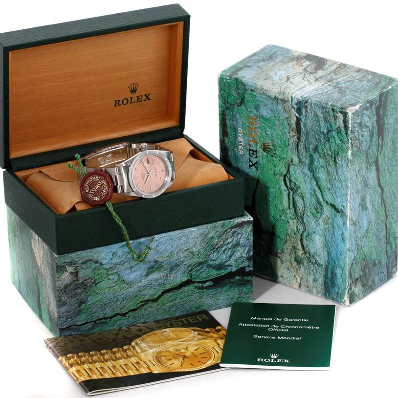 The image shows a Rolex Date 15210 Men's Stainless Steel Pink Dial 15210 Men's Stainless Steel Pink Dial watch and its accessories at an angle displaying the open box, watch, and instructional booklets.