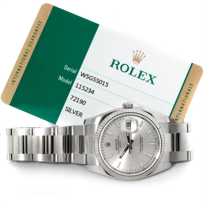 The image shows a Rolex Date 115234 Men's Stainless Steel Silver Dial 115234 Men's Stainless Steel Silver Dial model watch front-facing with its bracelet and an accompanying guarantee card.