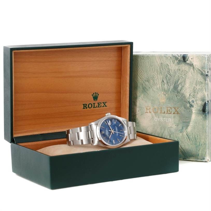 The Rolex Date 15200 Men's Stainless Steel Blue Dial 15200 Men's Stainless Steel Blue Dial watch is displayed in an open green and wooden box, showing its blue dial and silver bracelet.