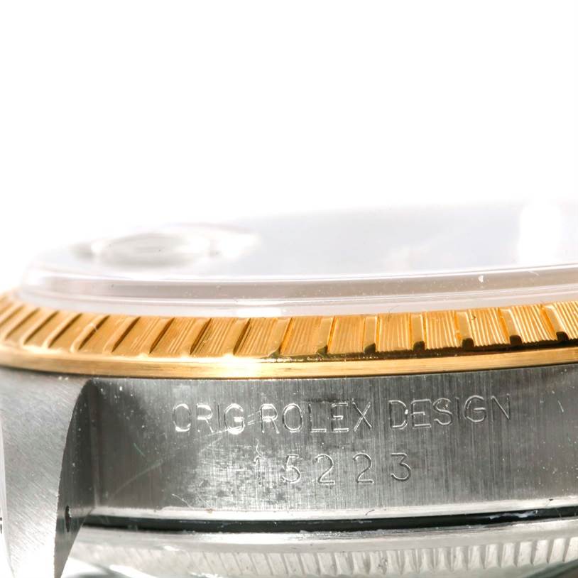 The image shows a close-up of the side of a Rolex Date 15223 Men's Steel and Gold (two tone) Champagne Dial 15223 Men's Steel and Gold (two tone) Champagne Dial model watch, highlighting the bezel and serial number engraving.
