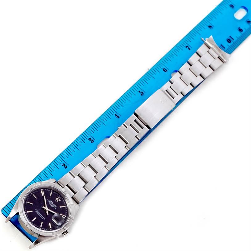 The image shows a Rolex Date 15210 Men's Stainless Steel Black Dial 15210 Men's Stainless Steel Black Dial model watch laid flat, positioned next to a ruler displaying the front face and the metal bracelet.