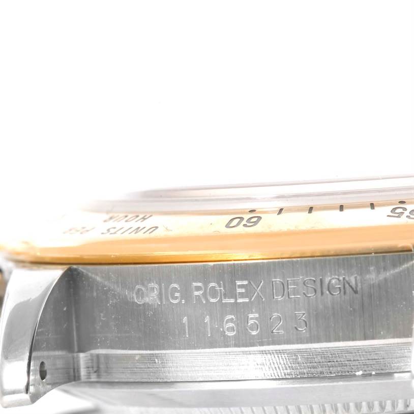 The image shows a side angle of a Rolex Daytona 116523 Men's Steel and Gold (two tone) Black Dial 116523 Men's Steel and Gold (two tone) Black Dial watch, focusing on the case edge with the model number and part of the bezel.