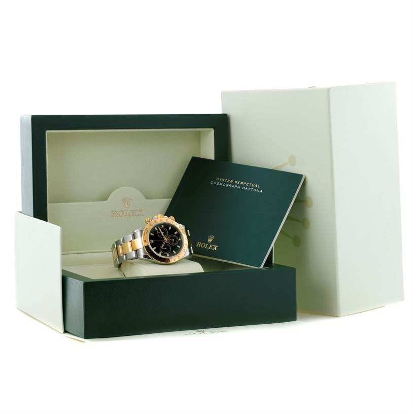 The Rolex Daytona 116523 Men's Steel and Gold (two tone) Black Dial 116523 Men's Steel and Gold (two tone) Black Dial watch is shown at an angled view, displayed inside its box with a booklet beside it.