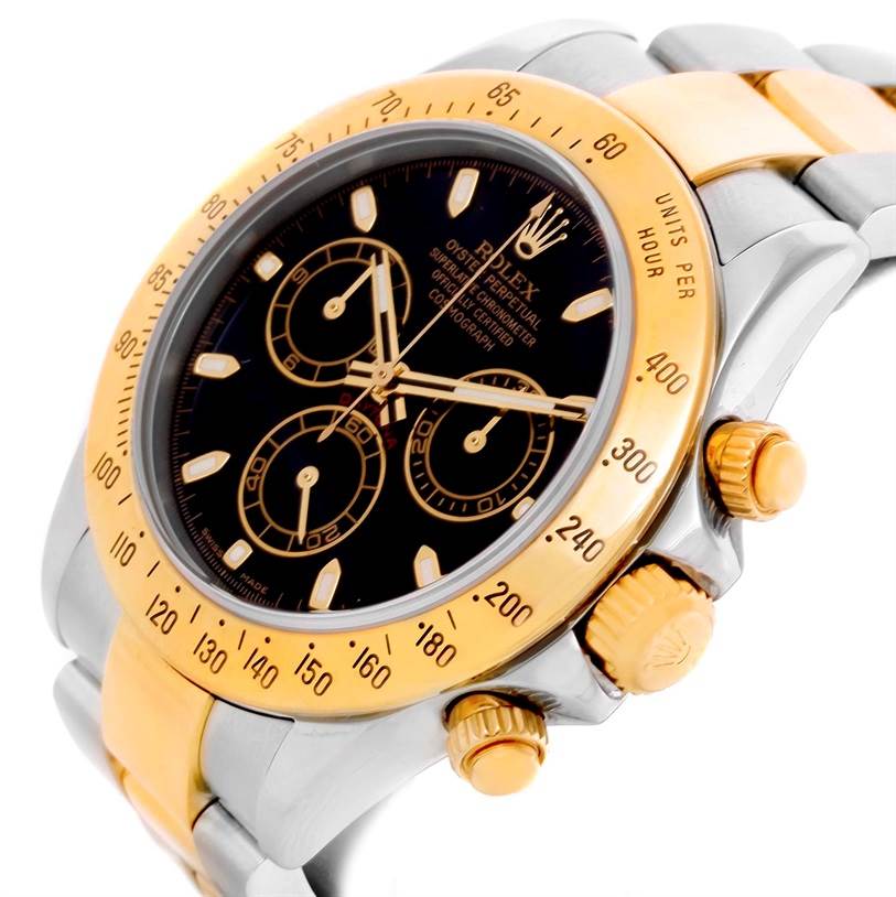 The image shows a close-up, angled view of a Rolex Daytona 116523 Men's Steel and Gold (two tone) Black Dial 116523 Men's Steel and Gold (two tone) Black Dial watch featuring its black dial, gold bezel, and chronograph pushers.