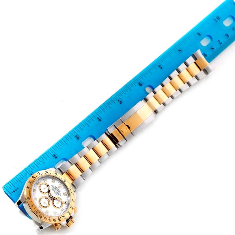 The image shows a Rolex Daytona 116523 Men's White Dial 116523 Men's White Dial watch laid next to a ruler, highlighting the face and band.