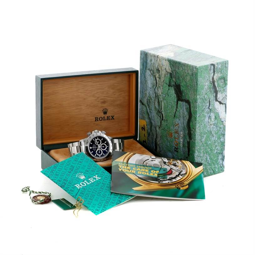 The image shows a Rolex Daytona 16520 Men's Stainless Steel Black Dial 16520 Men's Stainless Steel Black Dial watch displayed in an open box with accompanying manuals and tags.