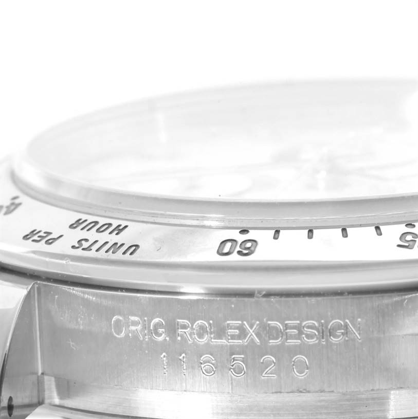 The image shows a close-up of the bezel, crystal, and engravings on the side of the Rolex Daytona 116520 Men's Stainless Steel White Dial 116520 Men's Stainless Steel White Dial watch.
