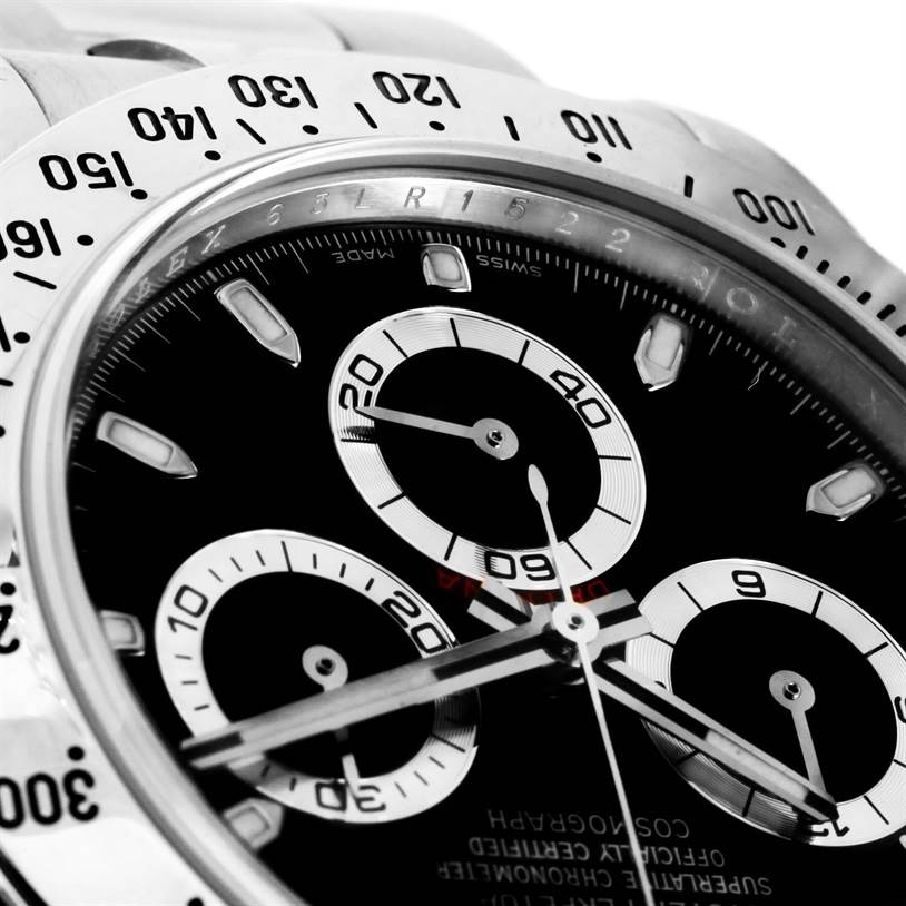 The image shows a close-up, angled view of a Rolex Daytona 116520 Men
s Stainless Steel Black Dial 116520 Men
s Stainless Steel Black Dial watch dial and part of its bezel, highlighting sub-dials and markings.