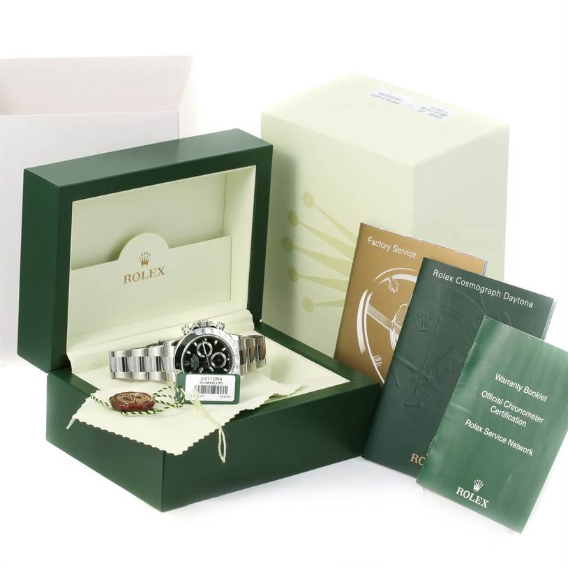 The image displays a Rolex Daytona 116520 Men's Stainless Steel Black Dial 116520 Men's Stainless Steel Black Dial watch in its box with accompanying booklets and accessories from a frontal angle.