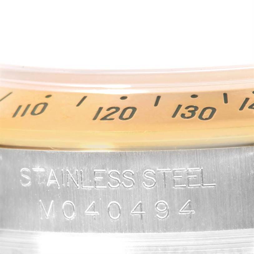 This close-up photo of the Rolex Daytona 116523 Men's Steel and Gold (two tone) Mother of Pearl Dial 116523 Men's Steel and Gold (two tone) Mother of Pearl Dial watch shows part of the bezel with its tachymeter scale and a portion of the stainless steel casing.